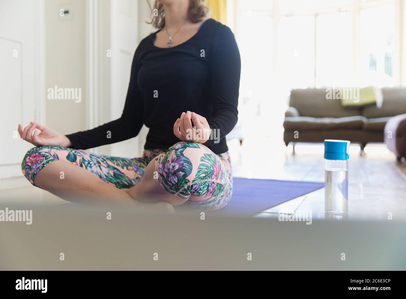 Donna che pratica la mediazione sul tappeto di yoga a casa Foto Stock