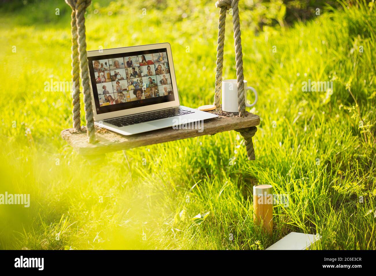 Video chat degli amici sullo schermo del computer portatile su una panca rustica in un giardino soleggiato Foto Stock