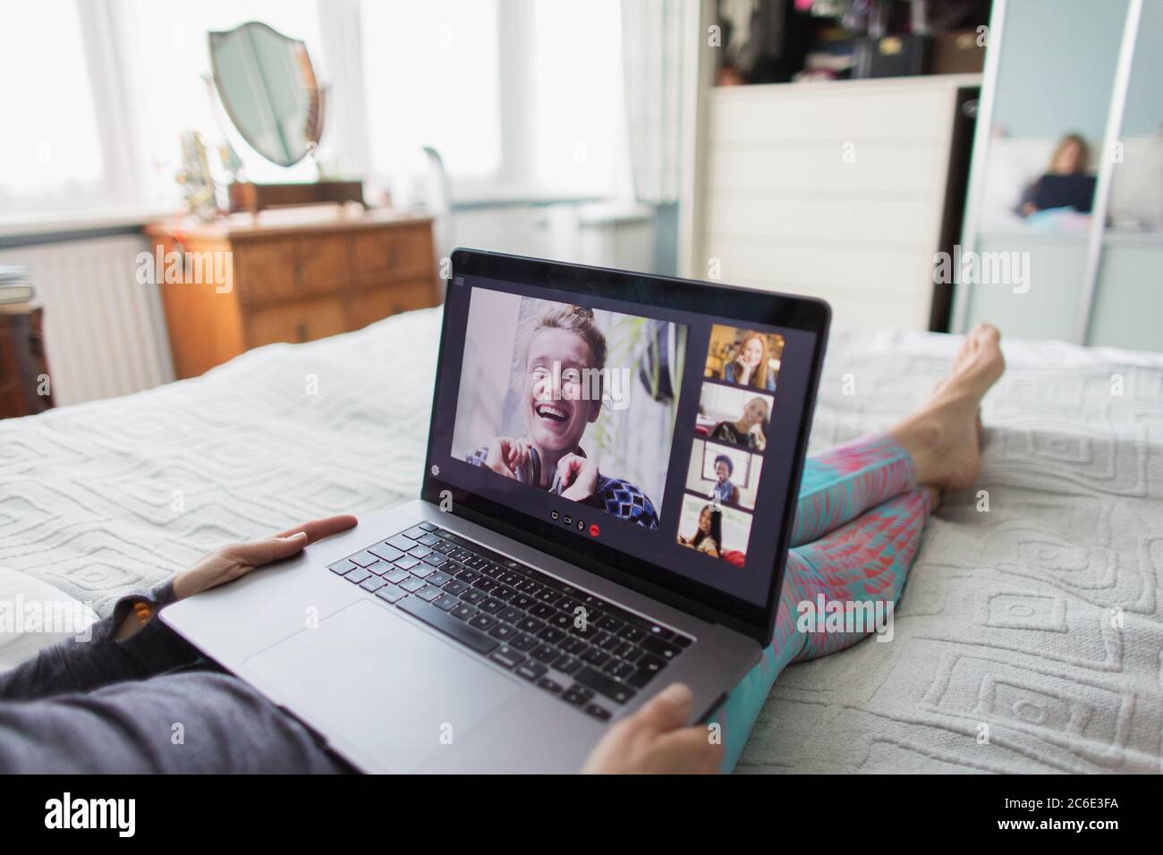 Donna con laptop che parla con gli amici a letto Foto Stock