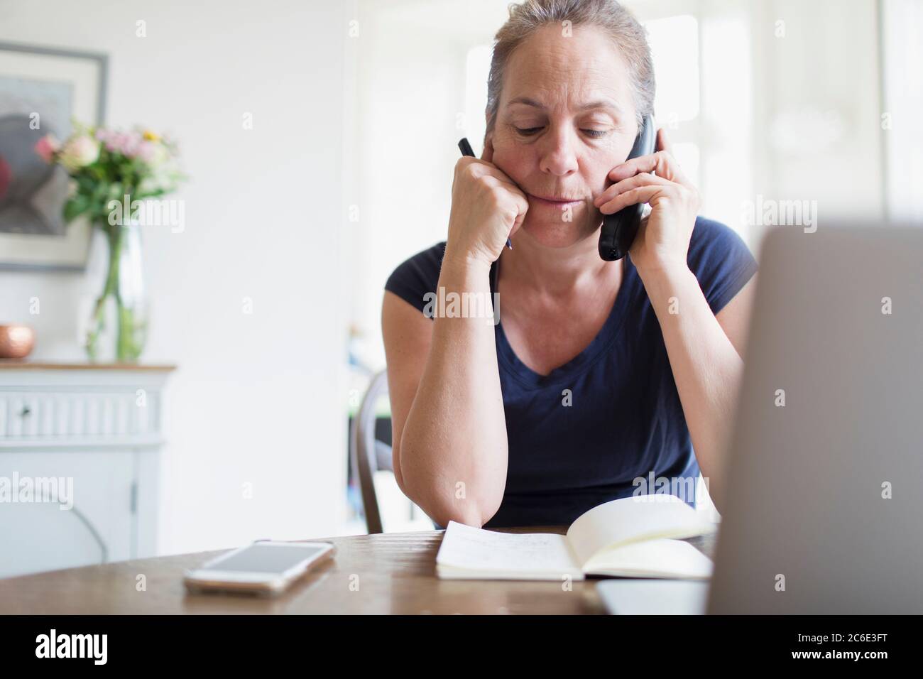 Donna che lavora da casa e parla al telefono Foto Stock