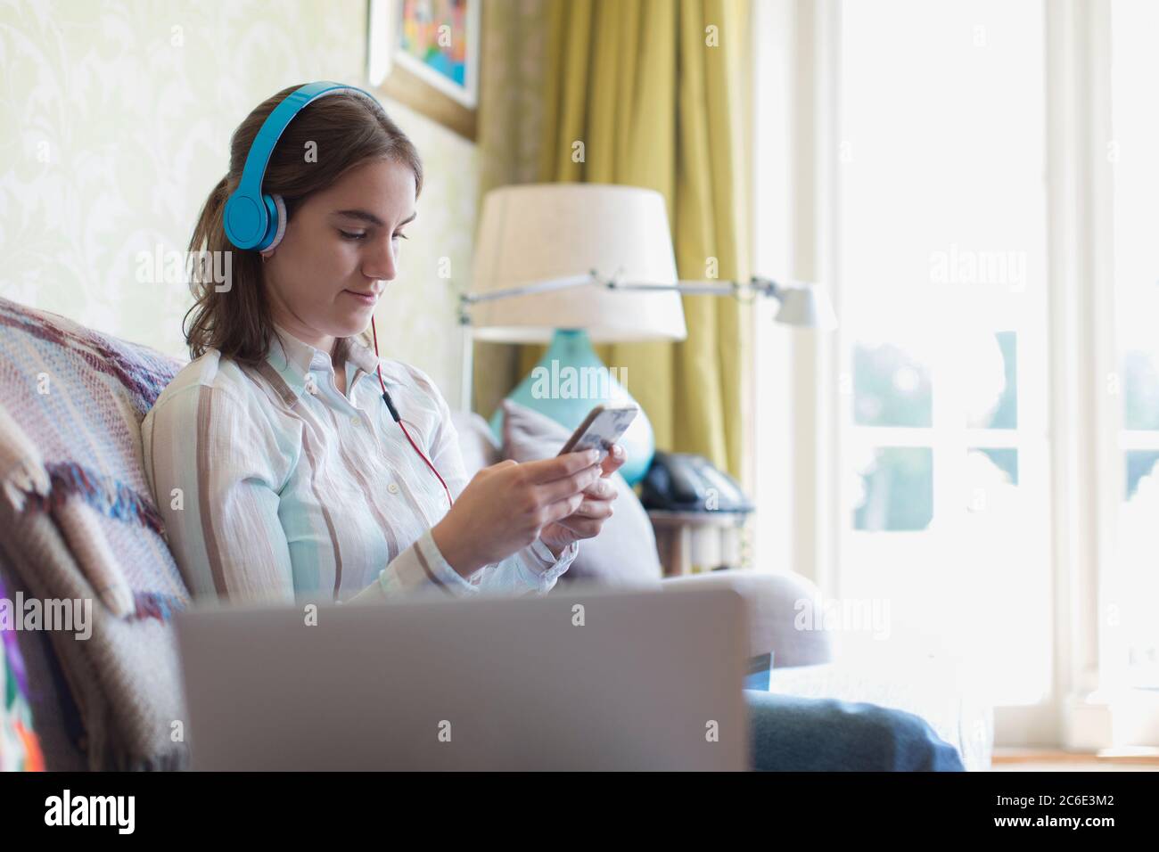 Ragazza adolescente con cuffie e smartphone sul divano Foto Stock