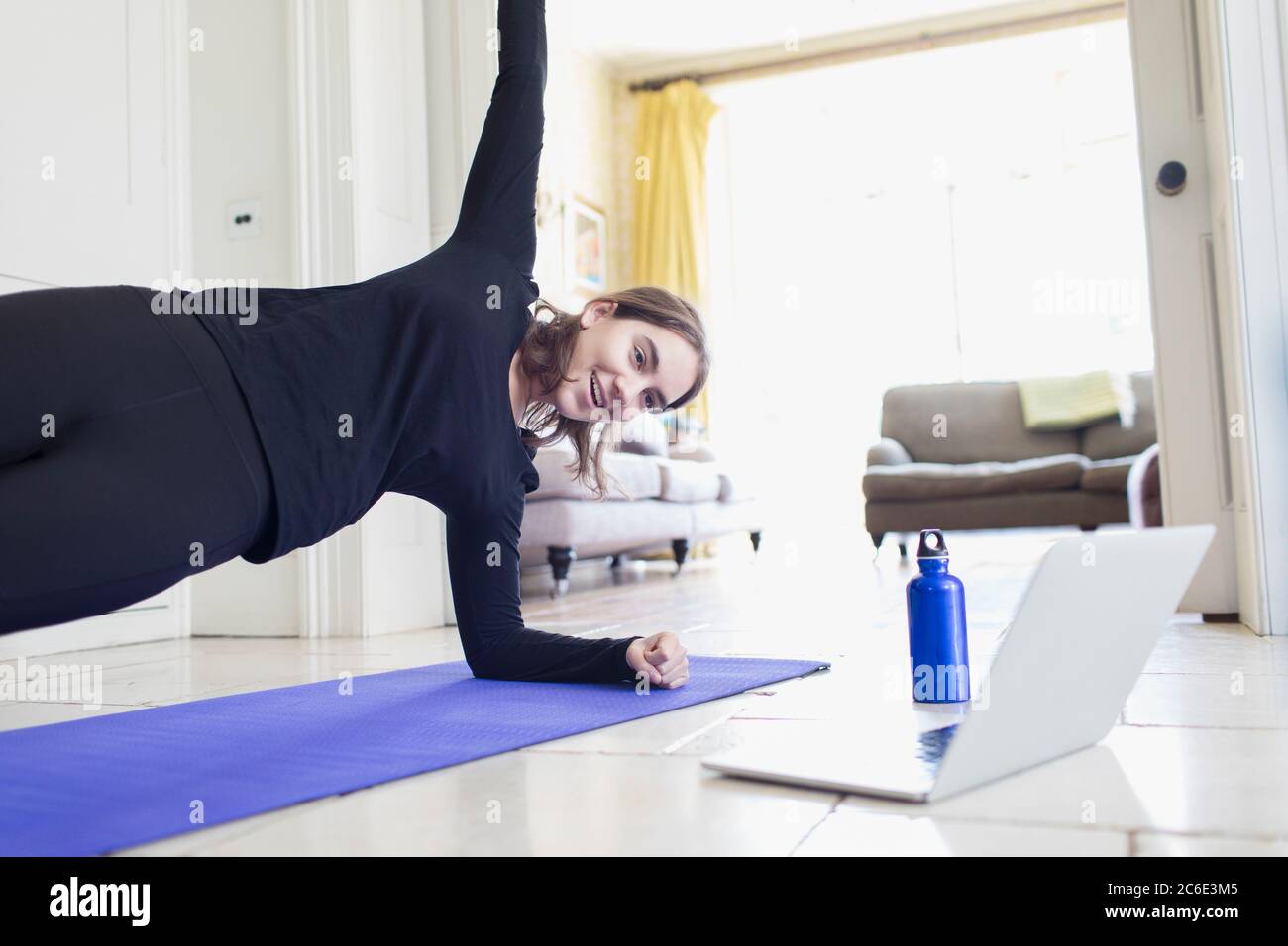 Adolescente ragazza che pratica yoga online al computer portatile a casa Foto Stock