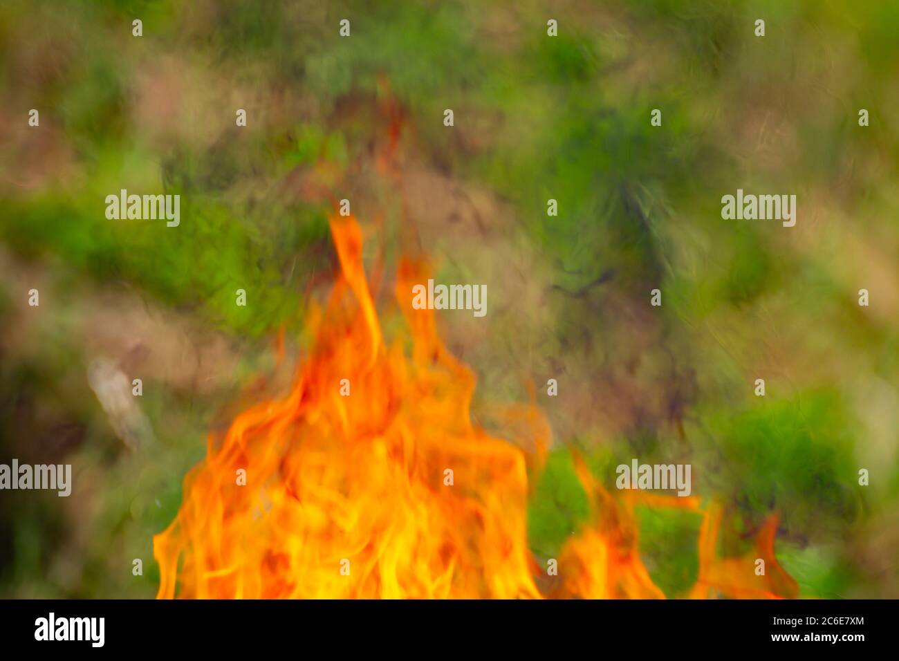Messa a fuoco morbida su fiamme sfocate con sfondo verde naturale Foto Stock
