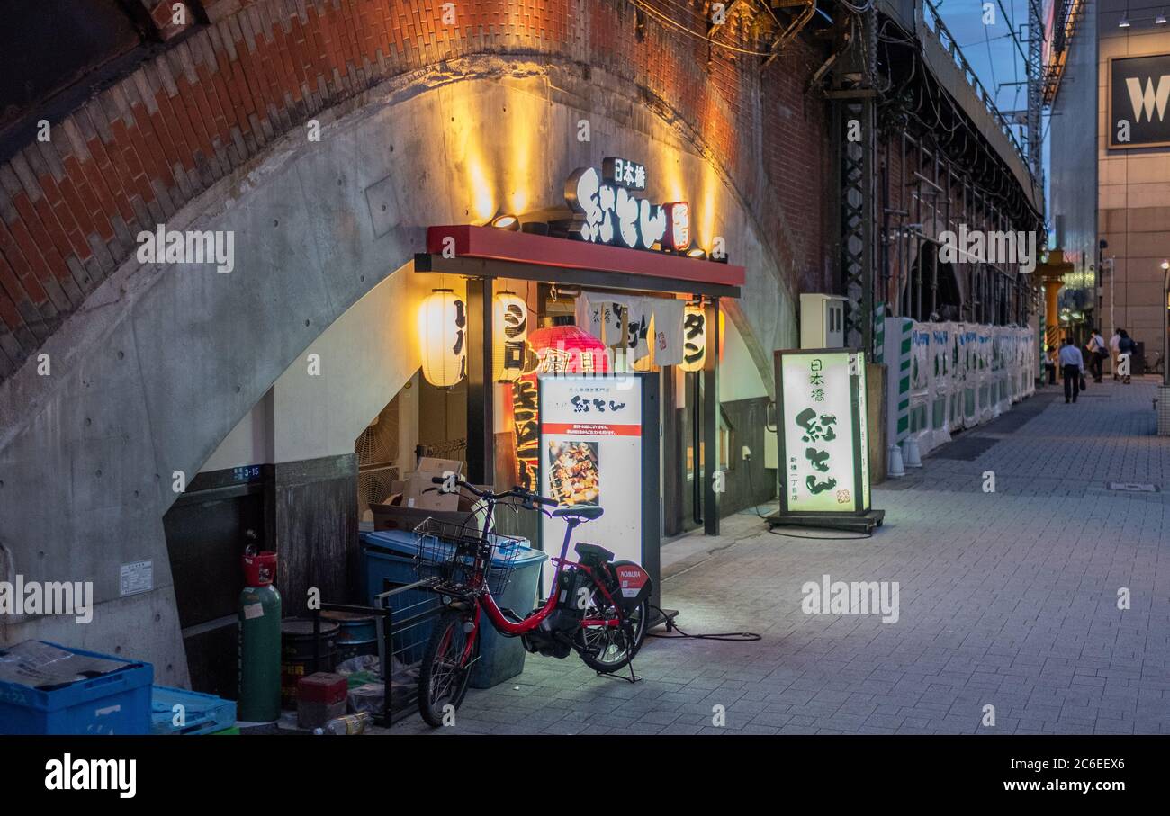 I vicoli della vecchia scuola del quartiere di Shimbashi o yokocho pieni di minuscoli ristoranti, pub e negozi, Tokyo, Giappone al tramonto. Foto Stock