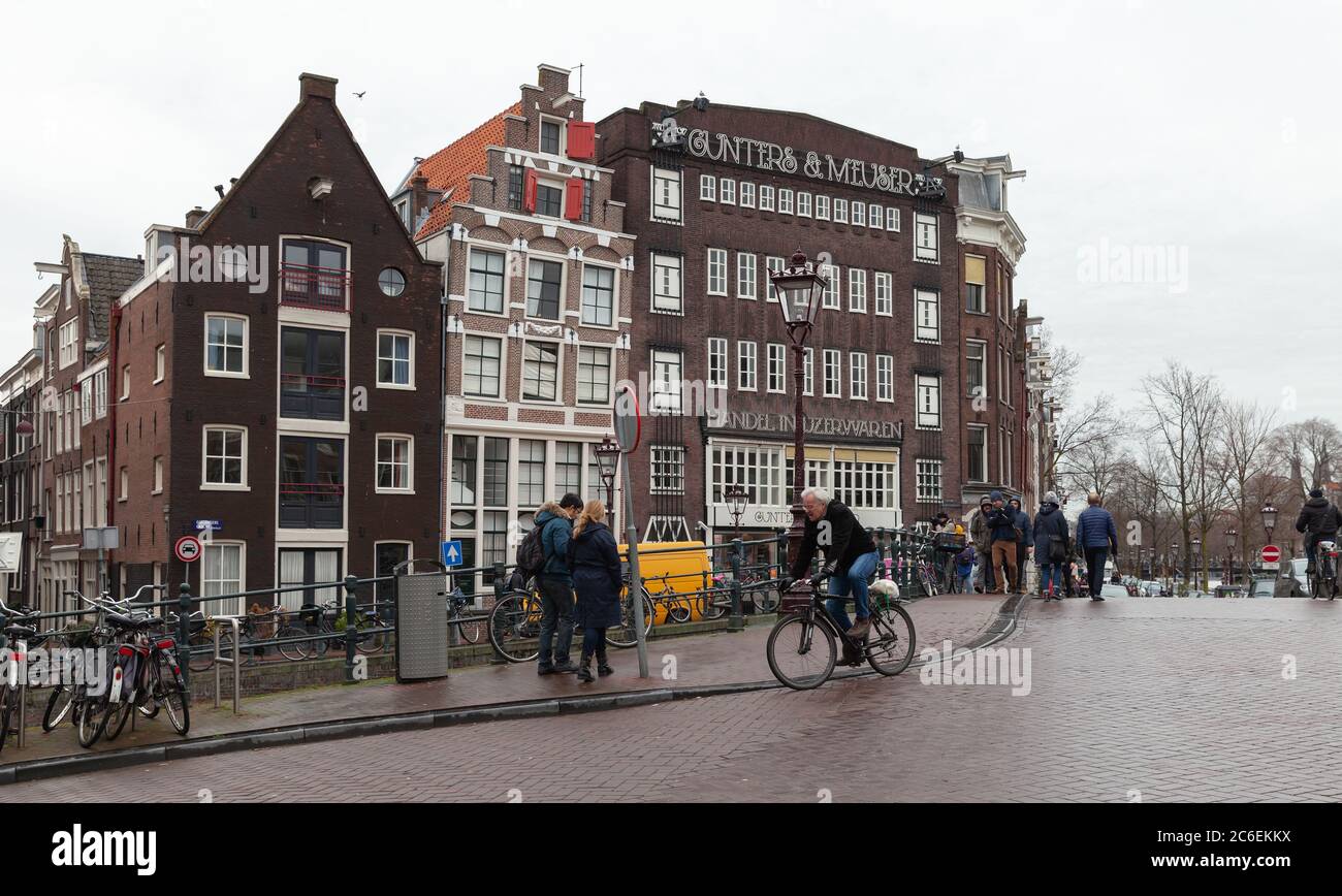 Amsterdam, Paesi Bassi - 25 febbraio 2017: StreetView della vecchia Amsterdam con vecchie case in mattoni. La gente comune è sulla strada Foto Stock