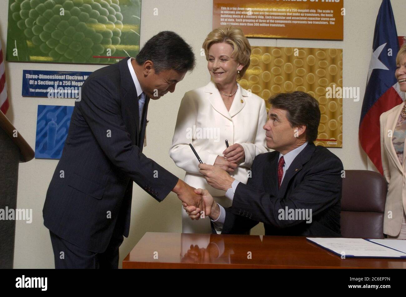 Austin, Texas USA, 13 giugno 2005: Il governatore del Texas Rick Perry (al centro, seduto) firma un disegno di legge che stimola gli investimenti nell'industria high-tech del Texas. La firma del disegno di legge avviene presso l'impianto di produzione di semiconduttori Samsung da 1,3 miliardi di dollari nella periferia nord di Austin. Da sinistra a destra ci sono il direttore dello stabilimento H.K. Park, la State Rep. Jeanne Morrison e il Gov. Perry. ©Bob Daemmrich Foto Stock