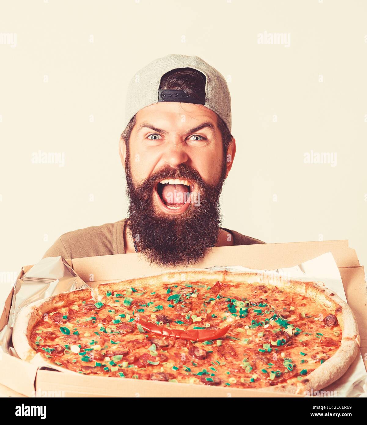 Giovane offre pizza Diavola. Il corriere per la consegna della pizza tiene la scatola in mano. Foto Stock