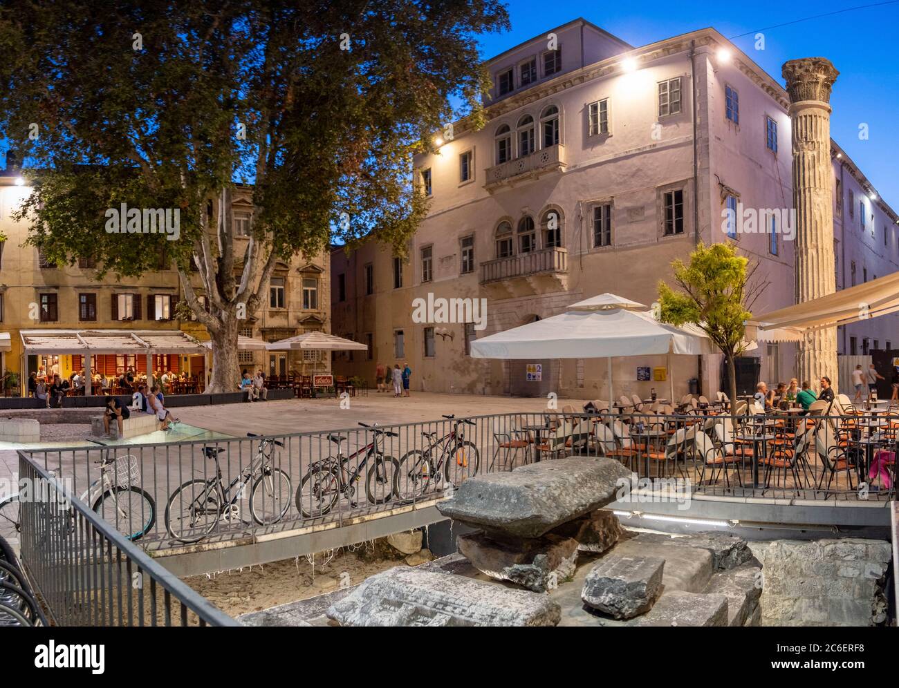 Colonna Romana intorno a plaza moderno con caffè e persone a notte, Zadar, Croazia Foto Stock