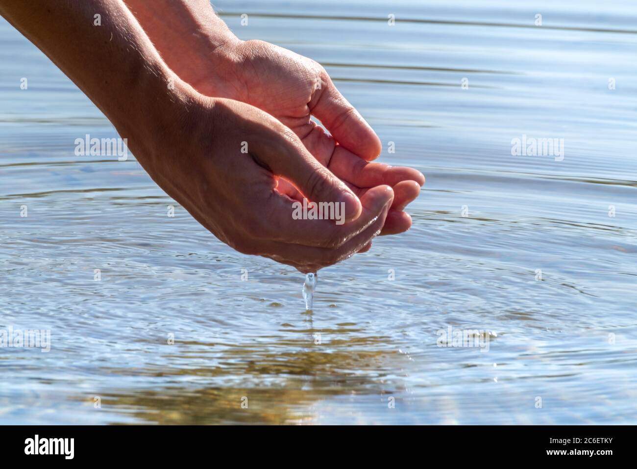 Primo piano di mani che tengono acqua con riflesso. Afferrare acqua pura  nelle mani gocce che cadono nella superficie dell'acqua Foto stock - Alamy