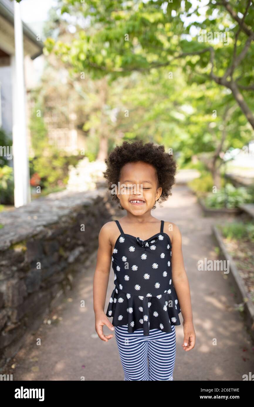 Giovane bella ragazza afroamericana in piedi in ambiente urbano con un'espressione carina, candida e felice. Foto Stock