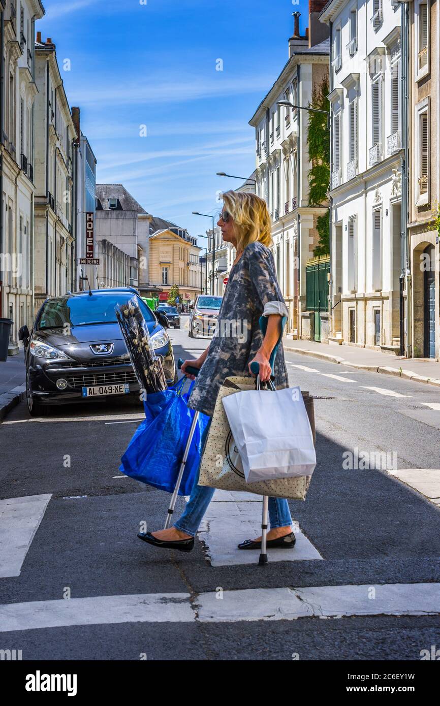 Donna negli anni '50 che trasporta borse per la spesa e che utilizza ausili  per camminare - Tours, Francia Foto stock - Alamy