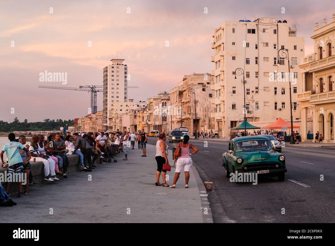 Un uomo cubano si trova all'interno di una classica auto d'epoca sul lato della strada a Habana Vieja a l'Avana, Cuba. Foto Stock