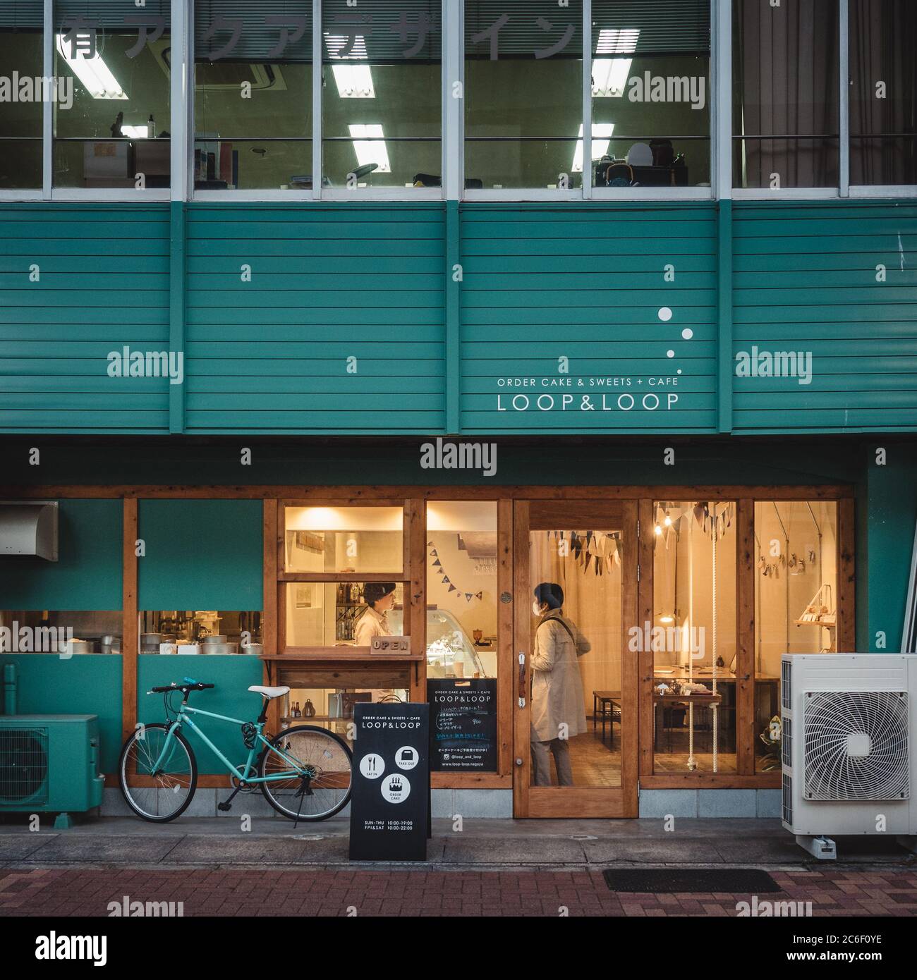 Nagoya, Aichi, Giappone - un piccolo caffè panificio a Tsurumai. Donna che compra torta e caffè. Vita quotidiana ordinaria nel villaggio. Illuminazione calda e atmosfera. Foto Stock