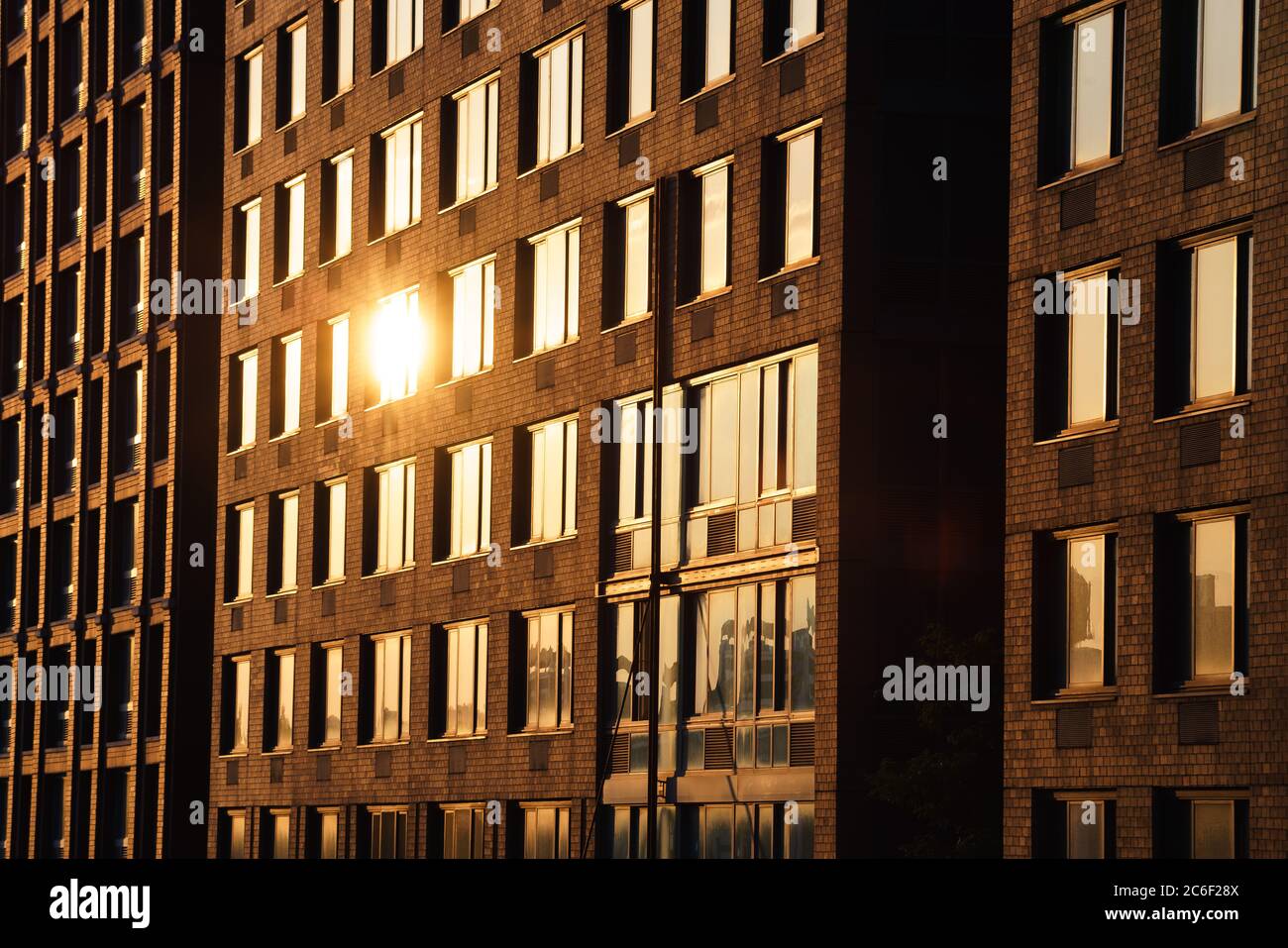 Il sole riflette su una finestra dell'edificio in mattoni di New York City durante il tramonto Foto Stock