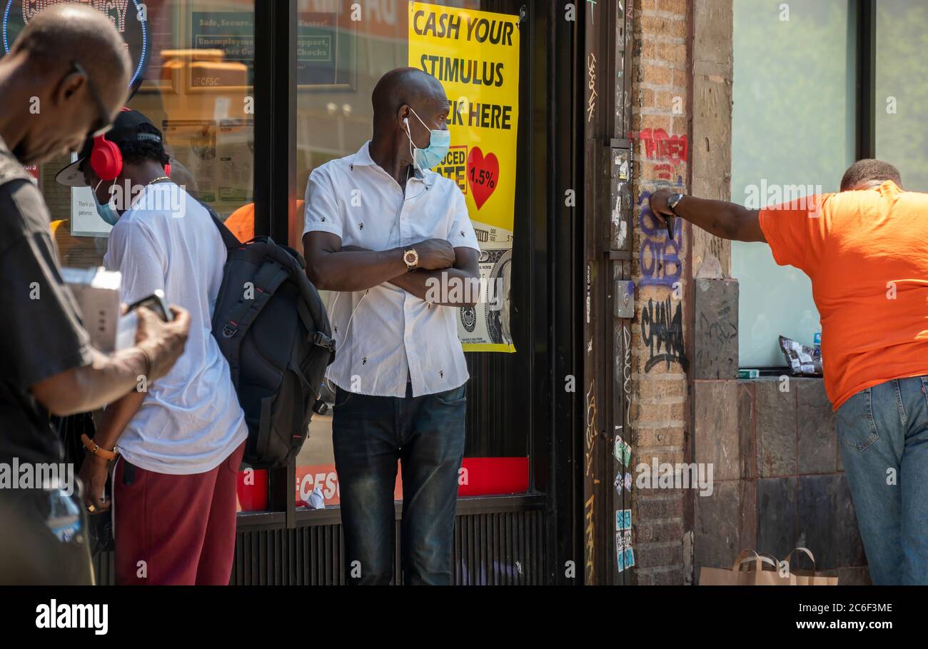 I clienti si allineano fuori da un'attività di cassa di controllo a Harlem a New York sabato 4 luglio 2020 che fa pubblicità che essi contanti incentivi assegni. (© Richard B. Levine) Foto Stock