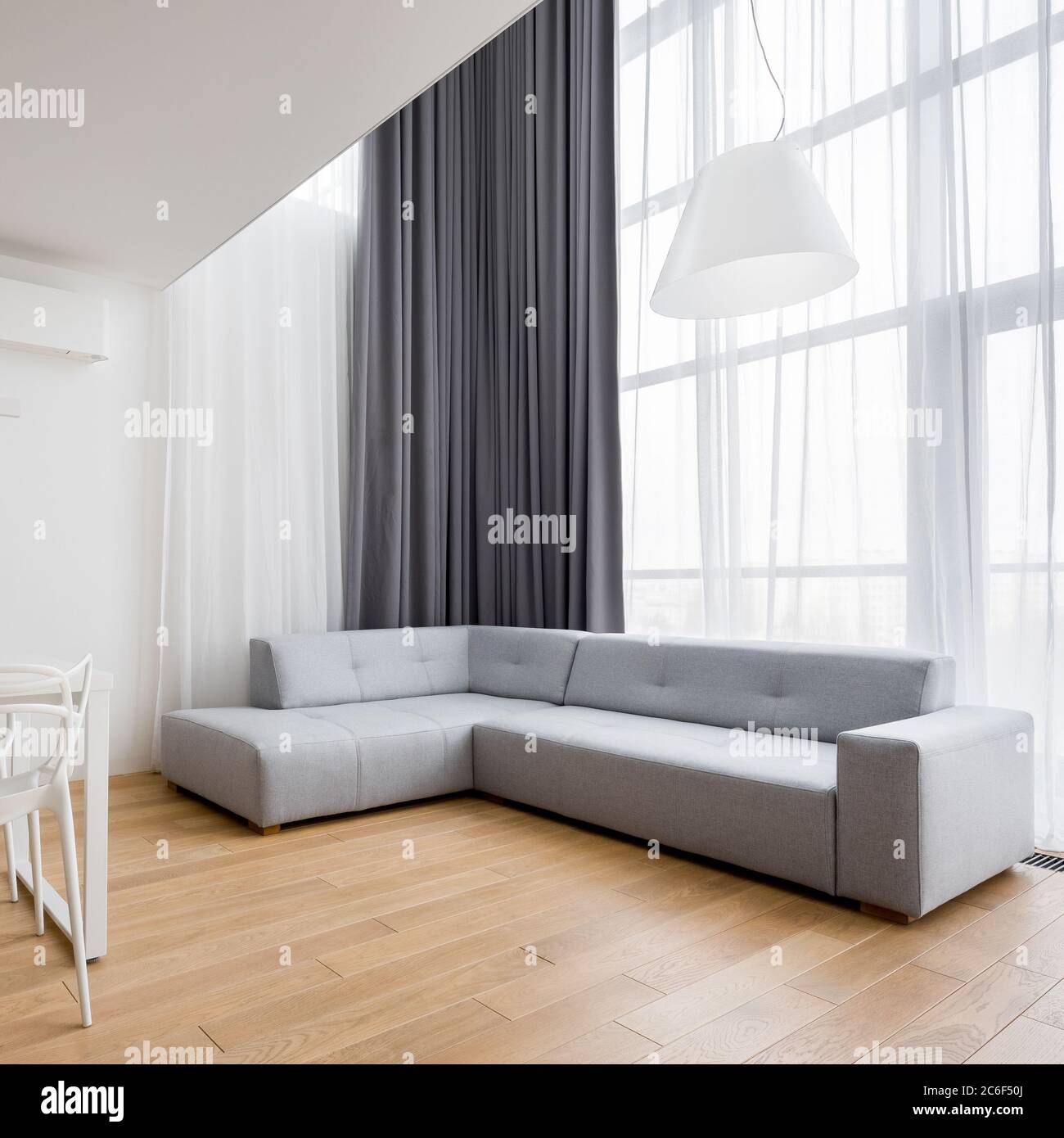 Home interno con divano ad angolo e nuovo design sedie bianche Foto Stock