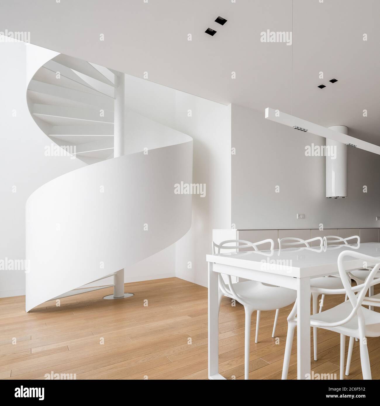 Interno a casa a pianta aperta con scale a spirale e tavolo bianco Foto Stock