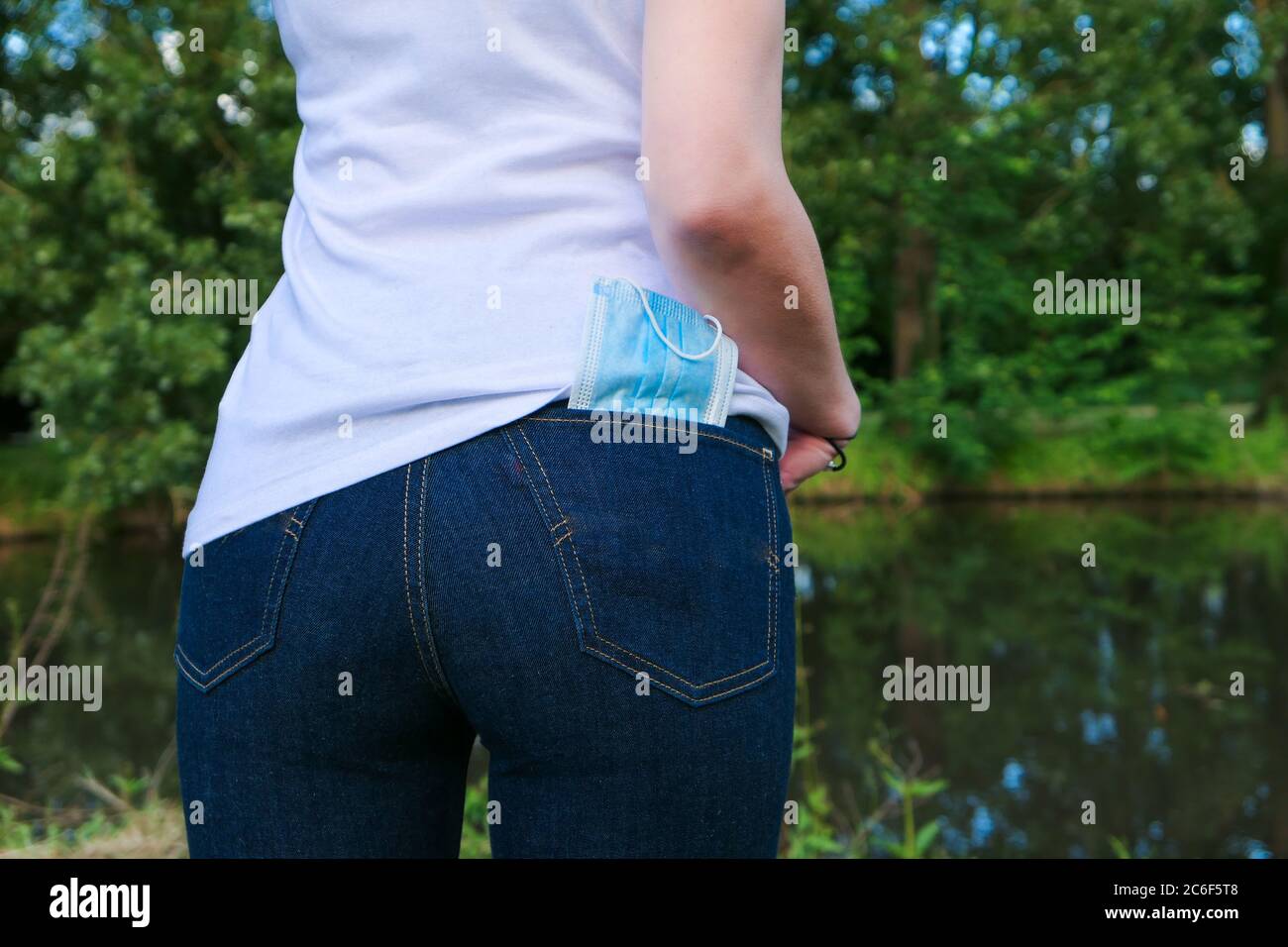 Maschera chirurgica conservata nella tasca posteriore dei pantaloni di una donna. Vista ravvicinata esterna. Protezione contro il coronavirus. Concetto antivirale. Foto Stock