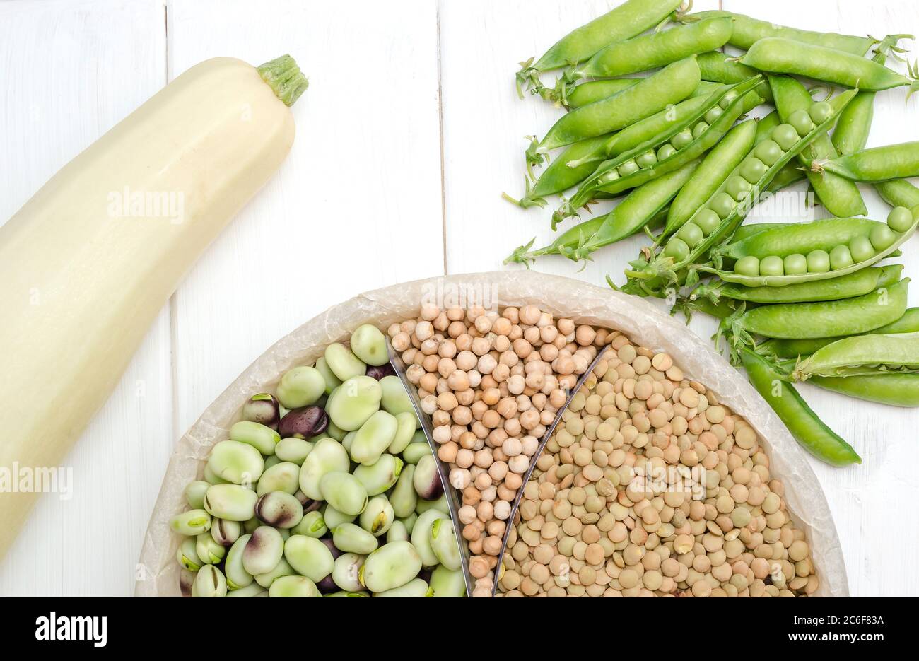 Una fonte vegetariana di proteine è lenticchie, piselli, ceci e fagioli. Vista dall'alto su un tavolo bianco. Foto Stock