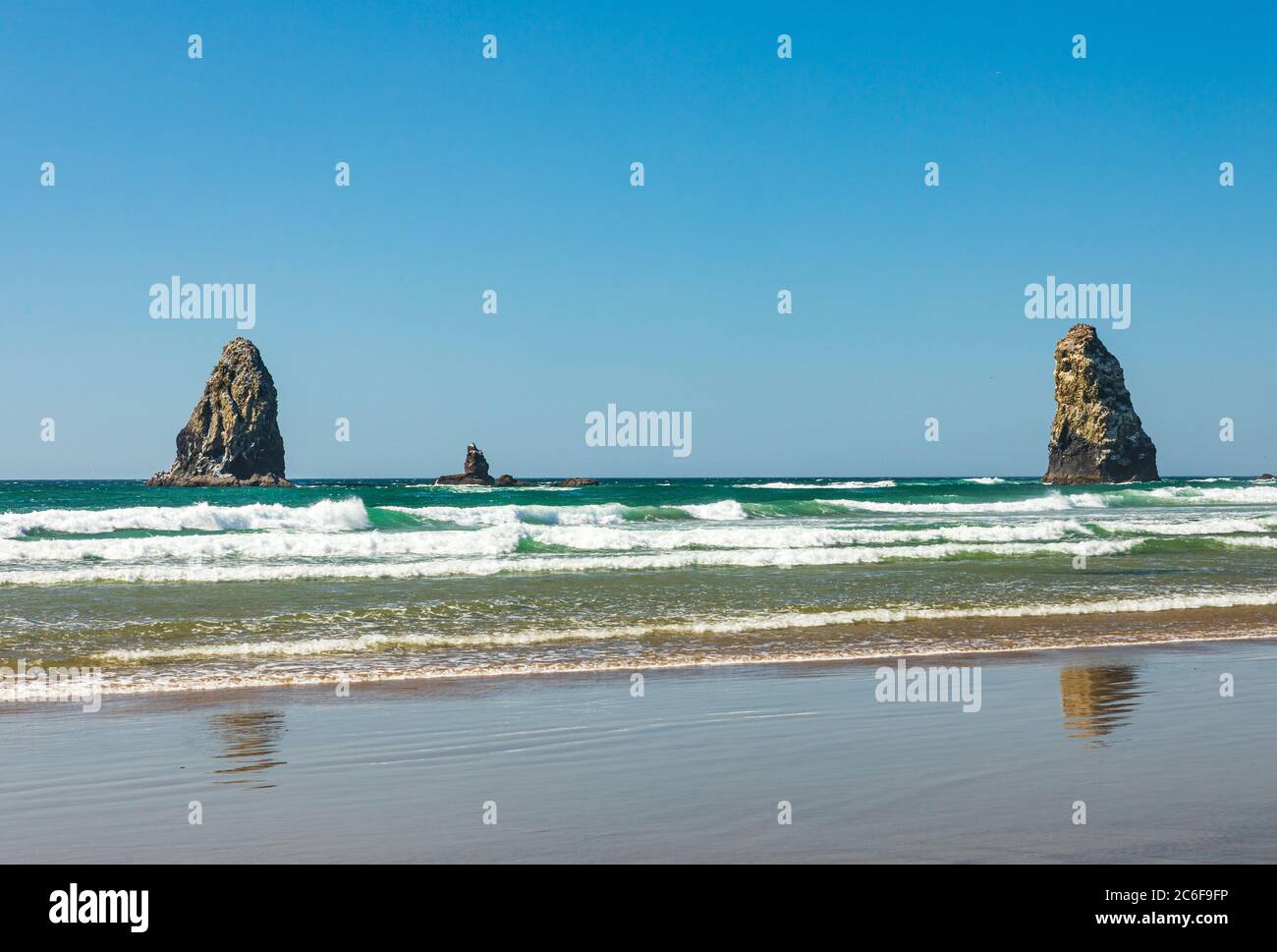 Le rocce di Sea Stack si ergono alte mentre le onde si tuffano su Cannon Beach in Oregon Foto Stock