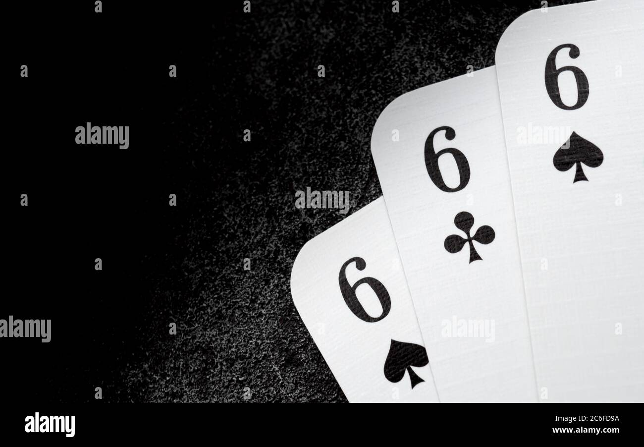 carte da gioco bianche 666 sei di picche e sei di mazze nell'angolo  inferiore destro sulla superficie in ghisa nera con spazio di copia sul  lato sinistro, triplice sei Foto stock -
