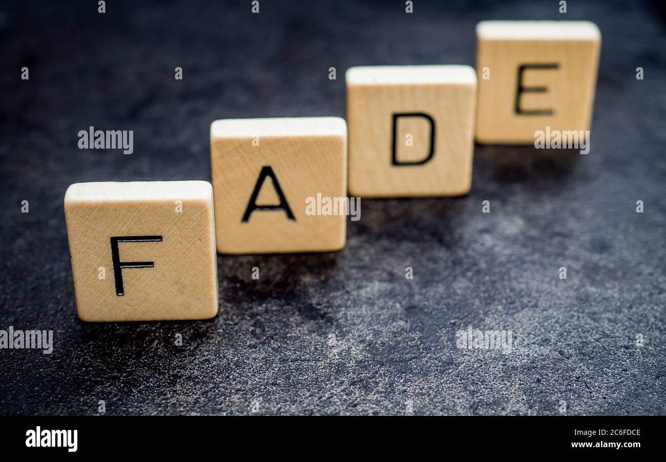 piastrelle in piedi di legno lettera formare parole su una superficie di ghisa grigia sullo sfondo, sbiadire, luce e ombra Foto Stock