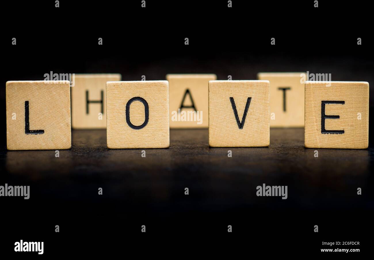 piastrelle in piedi di legno lettera formare parole su una superficie di ghisa grigia sullo sfondo, amore, odio Foto Stock