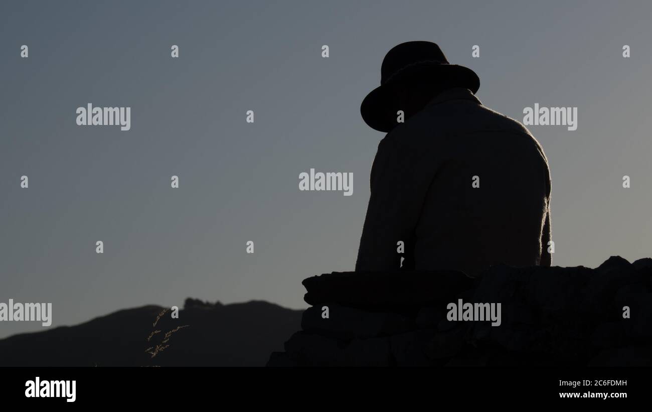 Silhouette di un uomo irriconoscibile con cappello all'alba Foto Stock