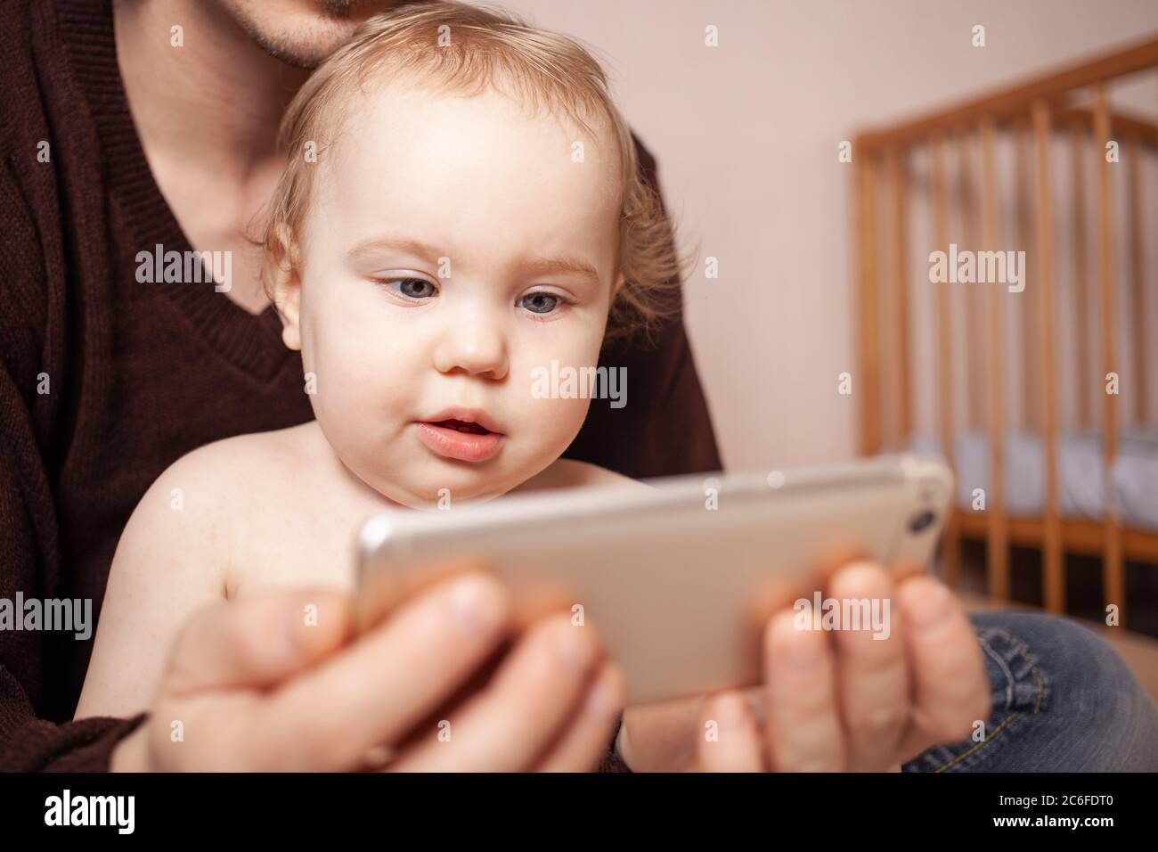 I genitori con la figlia di guardare video sul telefono cellulare a casa, famiglia giovane coppia con bambina utilizzando app per l'istruzione o il controllo di reti sociali Foto Stock
