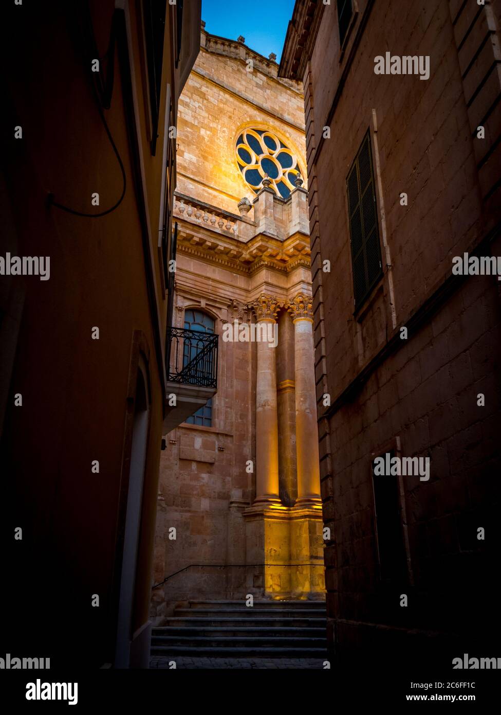 vista verticale della cattedrale neoclassica gotica di ciutadella de menorca da un vicolo stretto nella città vecchia illuminato al crepuscolo, minorca Foto Stock
