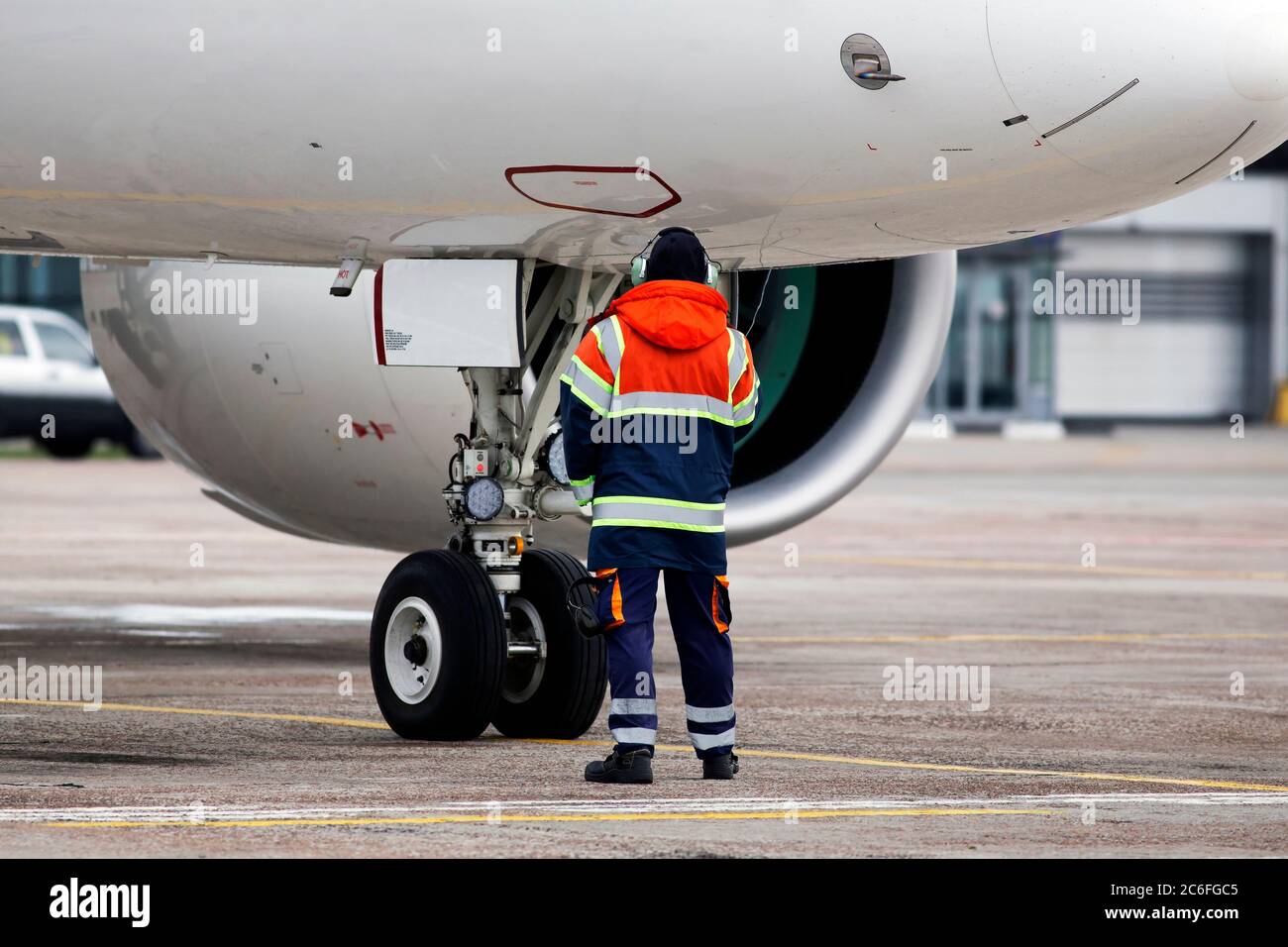 Un responsabile del controllo a terra aiuta a parcheggiare l'aereo nell'area di parcheggio dell'aeroporto Foto Stock