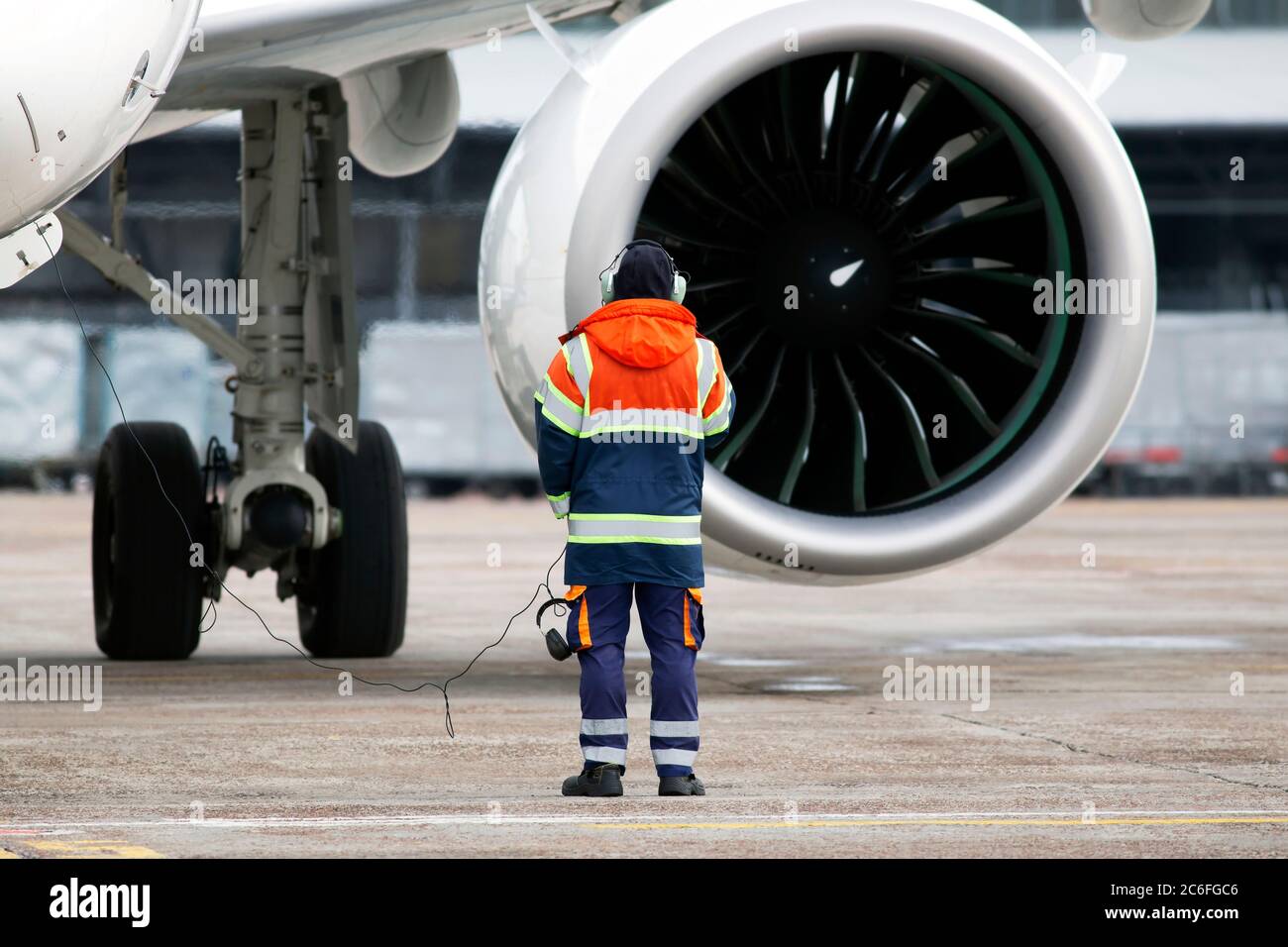 Un responsabile del controllo a terra controlla il processo di avviamento del motore del turbofan prima della partenza dell'aeromobile Foto Stock