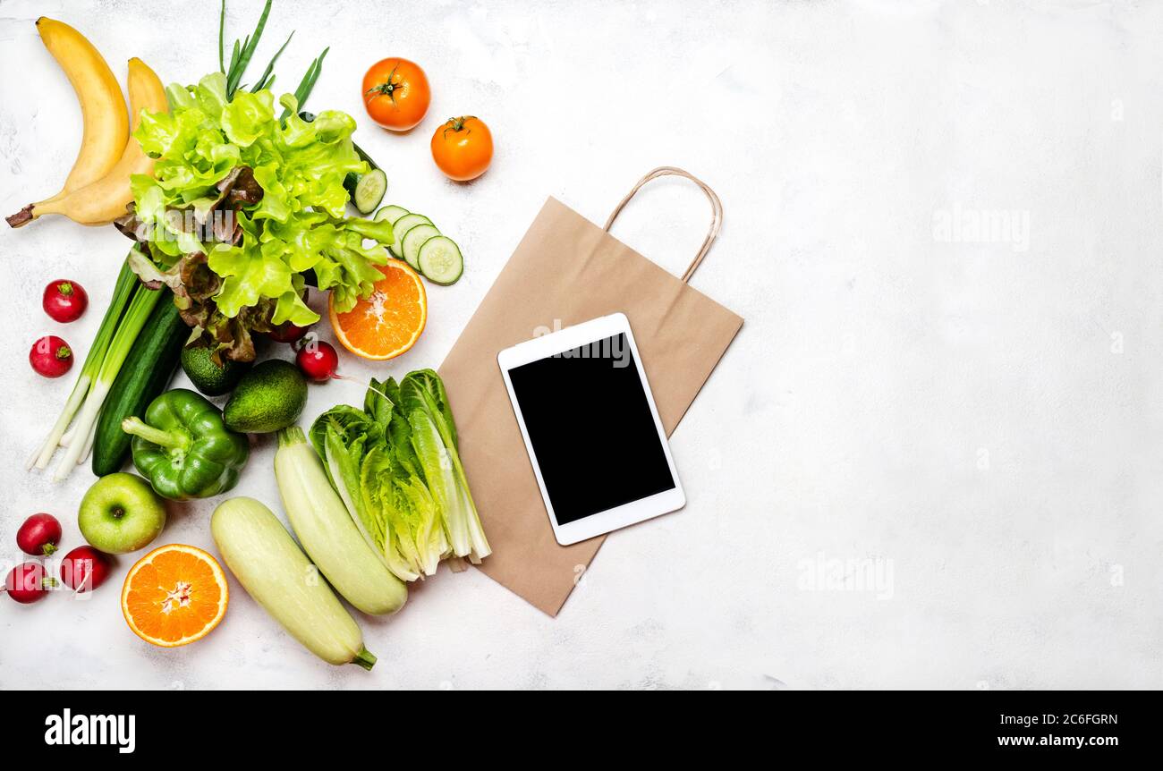 Concetto di cibo per la consegna. Borsa per la spesa in carta per computer con diverse verdure su sfondo bianco con vista dall'alto dello spazio per la copia. Foto Stock