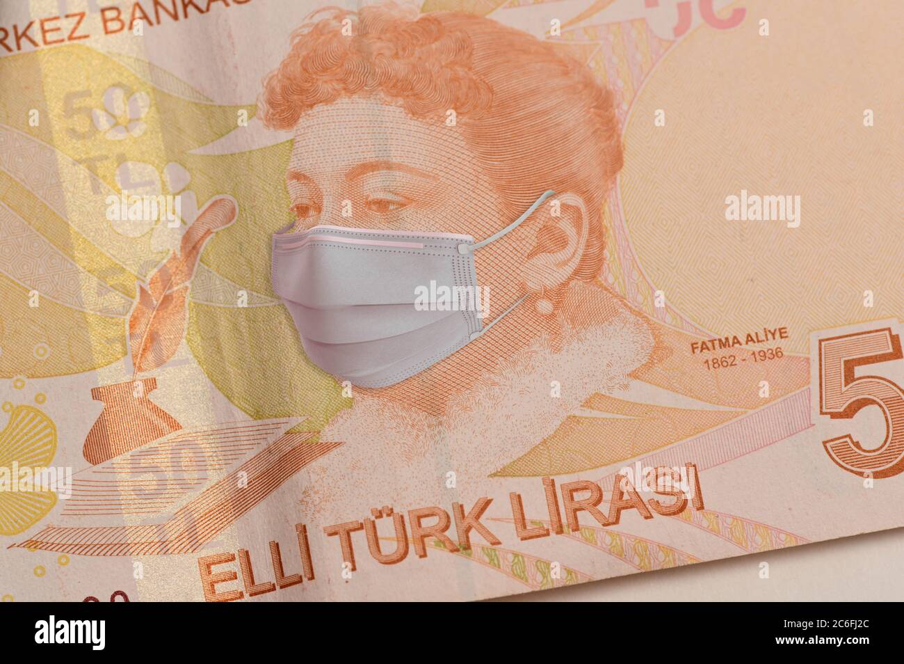 COVID-19 coronavirus in Turchia, 100 lira turca denaro con maschera facciale. Il coronavirus influisce sul mercato azionario globale. Foto Stock