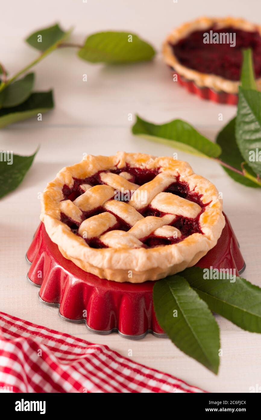 Torta aperta di pasta frolla con ciliegie e lamponi, una torta con una servietta su sfondo bianco Foto Stock