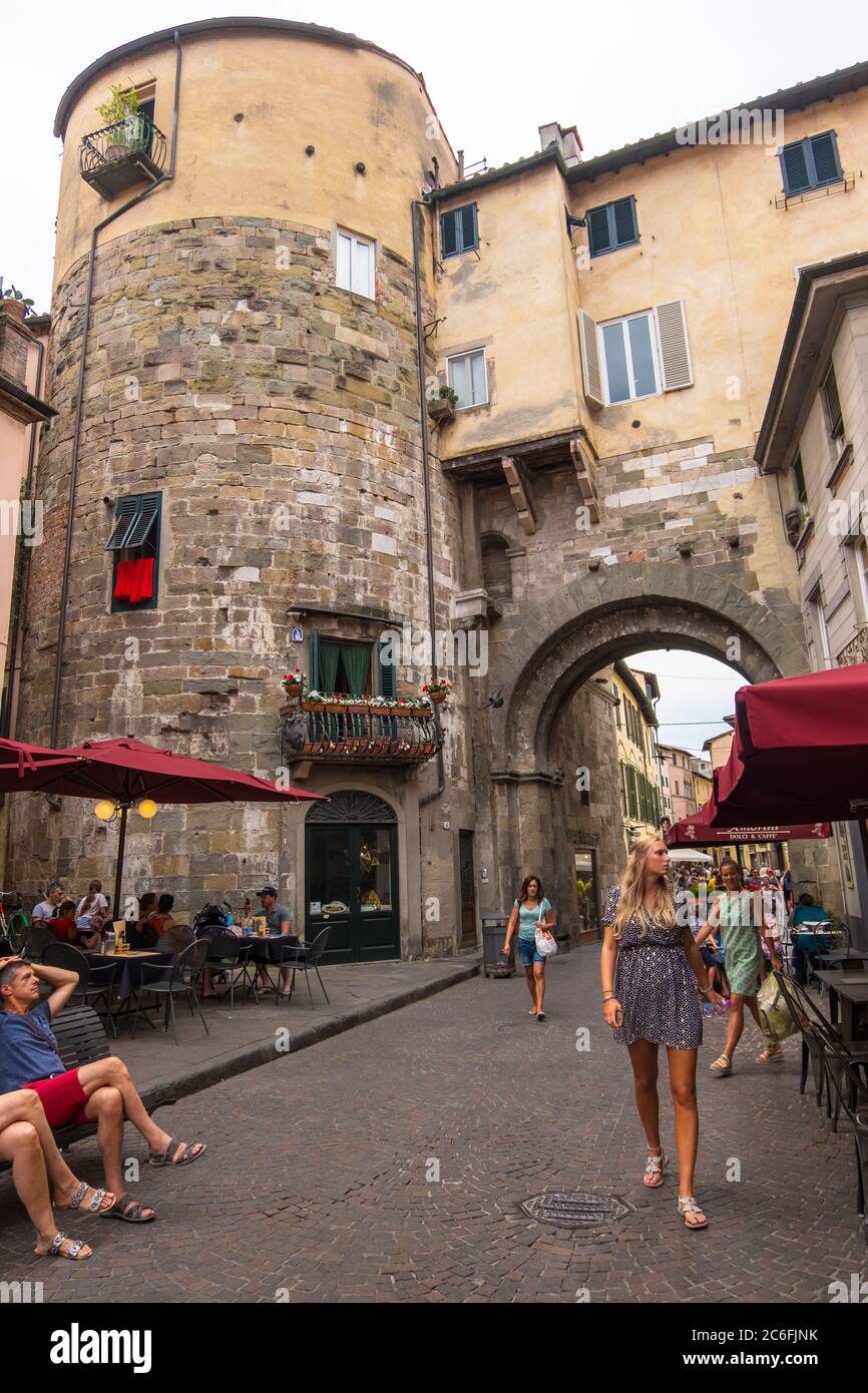 Lucca, Italia - 14 agosto 2019: Turisti e locali nella vecchia stradina medievale con caffè e negozi nel centro storico di Lucca, Toscana Foto Stock