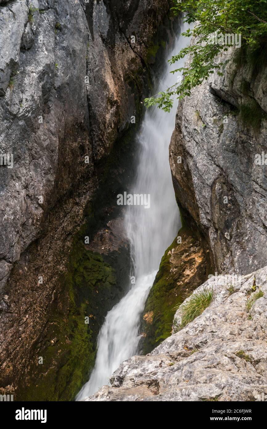 Piccola cascata lotta alla sorgente del fiume Soca nelle rocce della Valle del Trenta nel Parco Nazionale del Triglav in Slovenia. Foto Stock