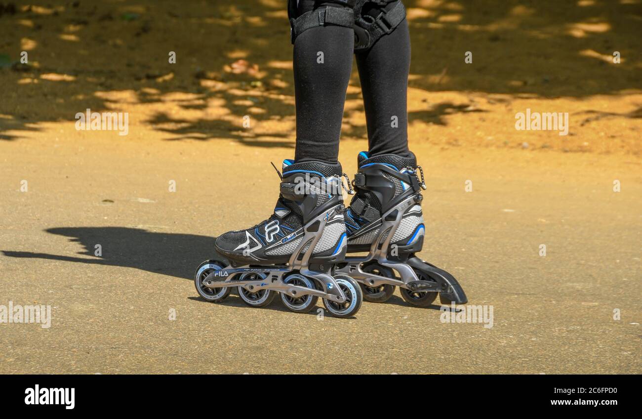 LONDRA, INGHILTERRA - LUGLIO 2018: Coppia di lame a rullo indossate da una giovane donna che si esercita in un parco pubblico. Foto Stock
