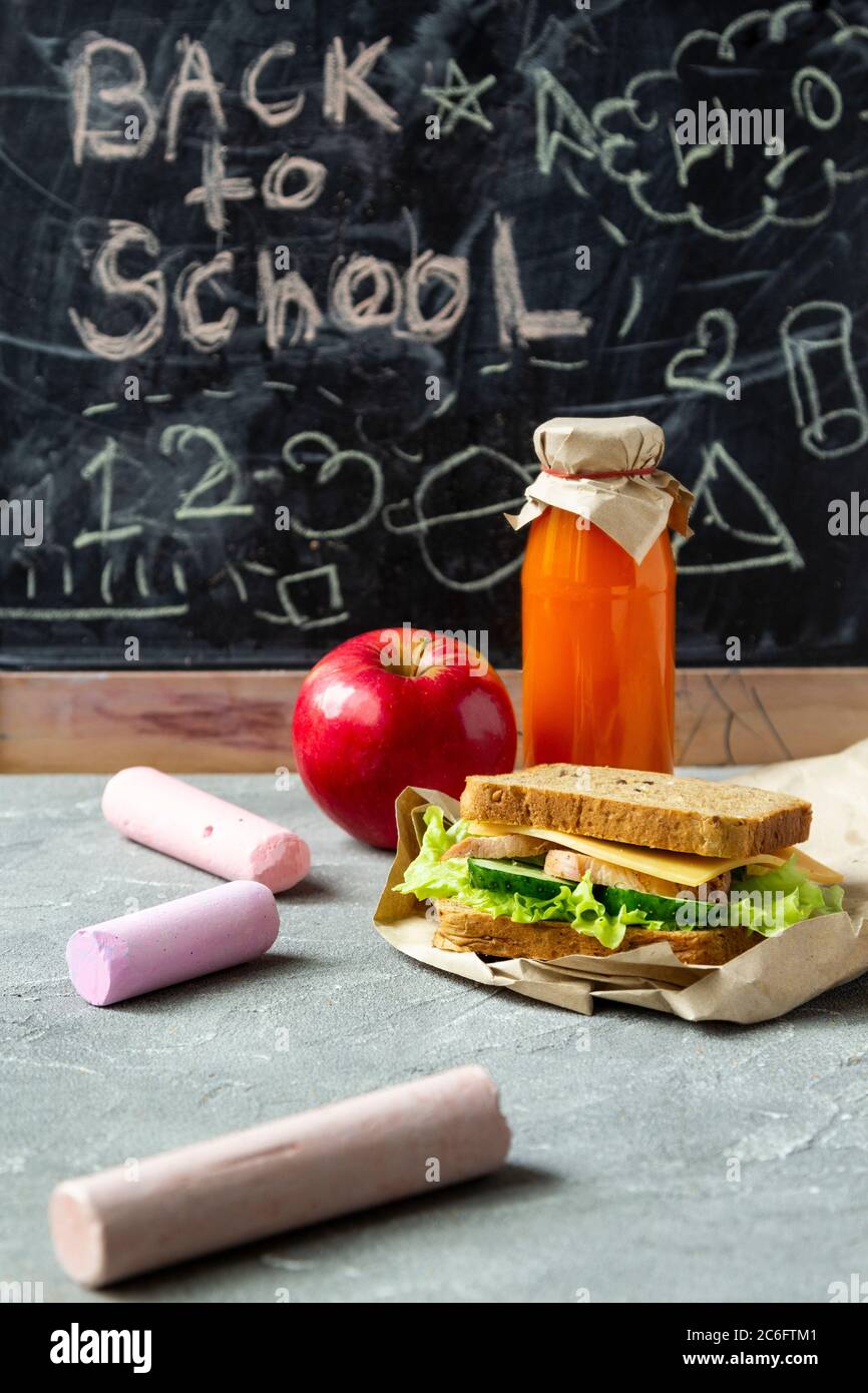 Pranzo sano scuola: Sandwich con insalata, formaggio e cetriolo, succo di frutta e mela. Nutrizione sana per i bambini. Pausa scolastica. Foto Stock