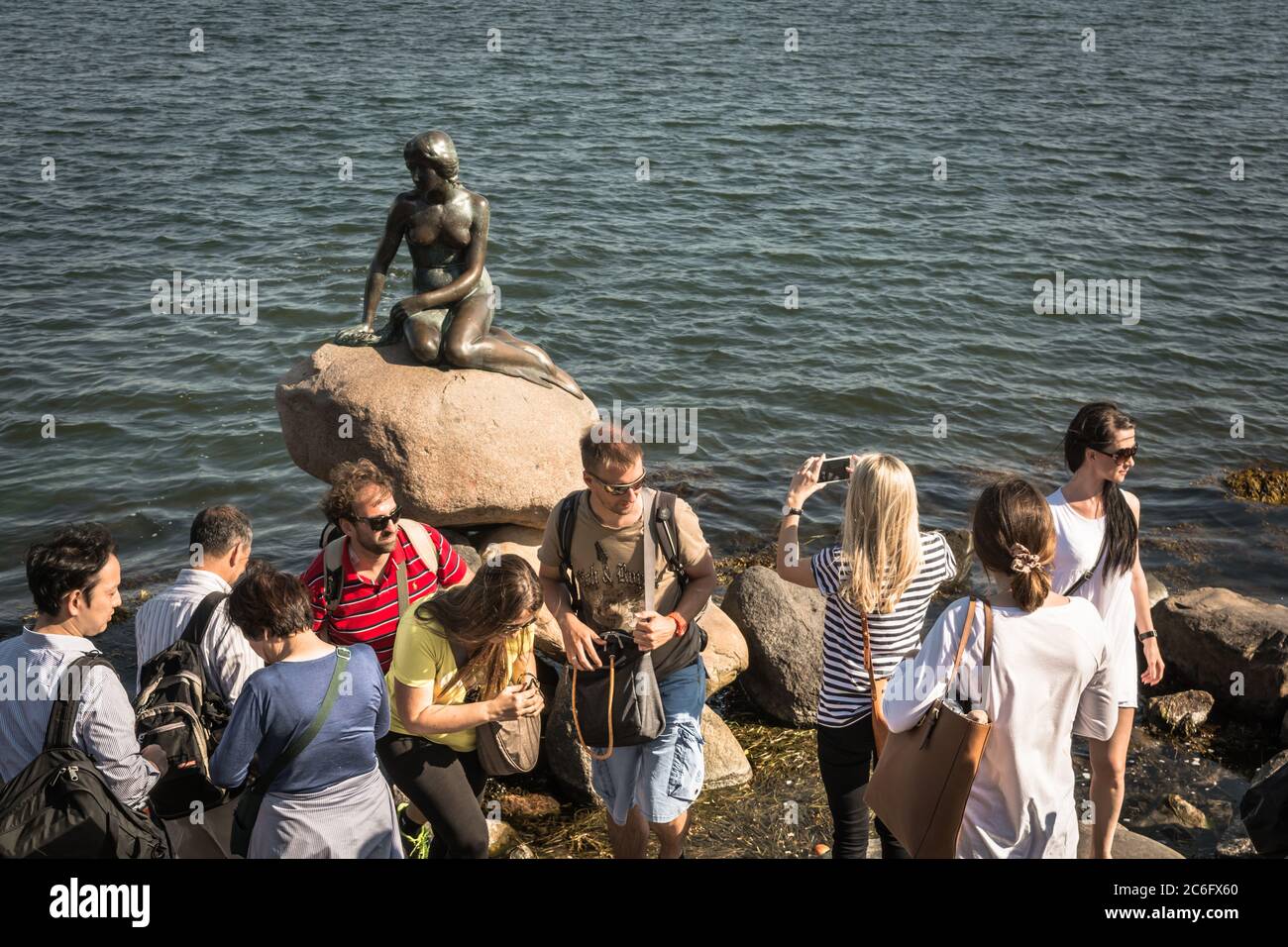 I turisti si sforzano di fotografare la statua della Sirenetta, Copenhagen, Danimarca Foto Stock