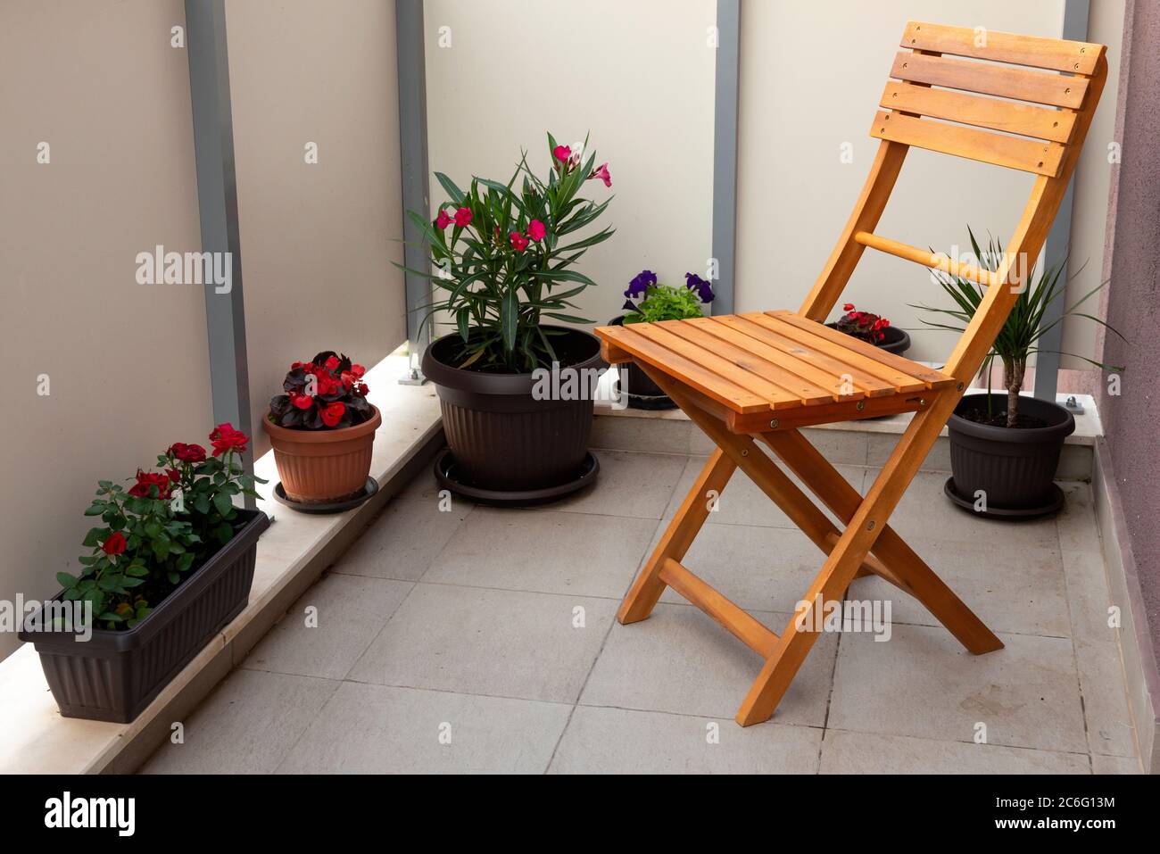 Semplice sedia in legno e fiori in vasi di fiori sul balcone dell'appartamento come floricoltura urbana a casa concetto. Foto Stock