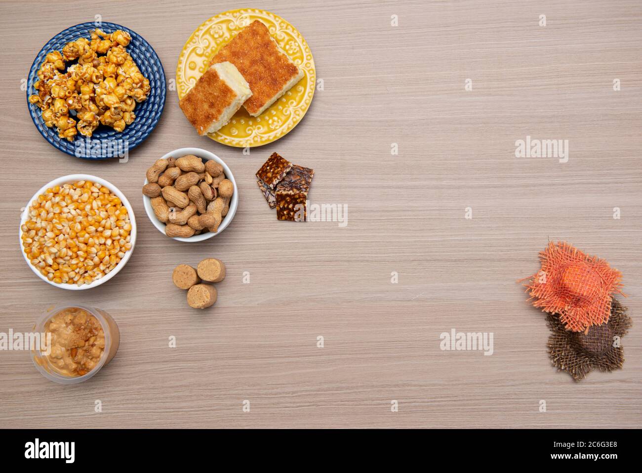 Vista dall'alto dei tipici cibi di giugno Party su un tavolo di legno: Popcorn, torta di farina di mais, noccioline, caramelle di arachidi (paçoca) e dulce de leche Foto Stock