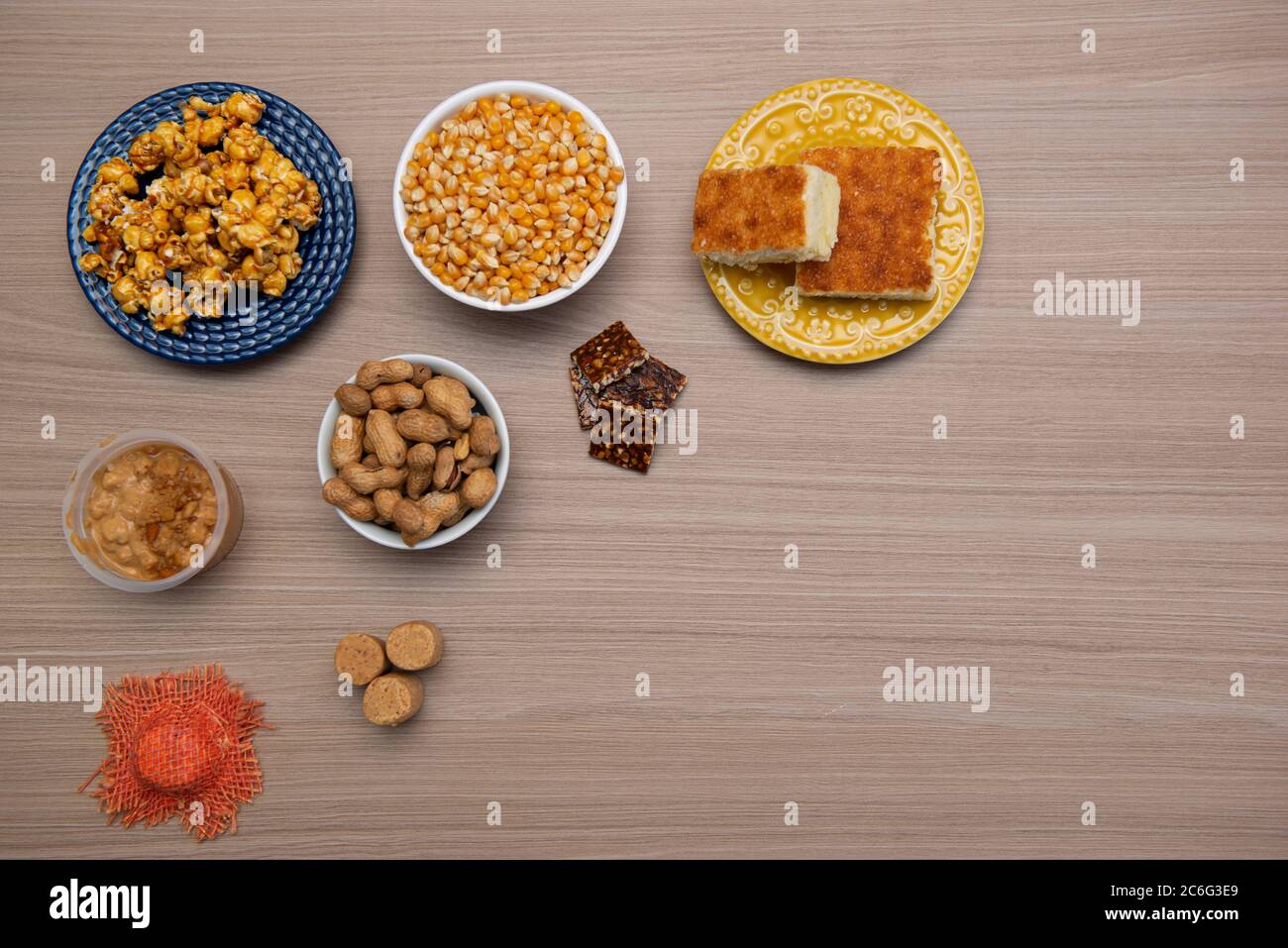 Vista dall'alto dei tipici cibi di giugno Party su un tavolo di legno: Popcorn, torta di farina di mais, noccioline, caramelle di arachidi (paçoca) e dulce de leche Foto Stock