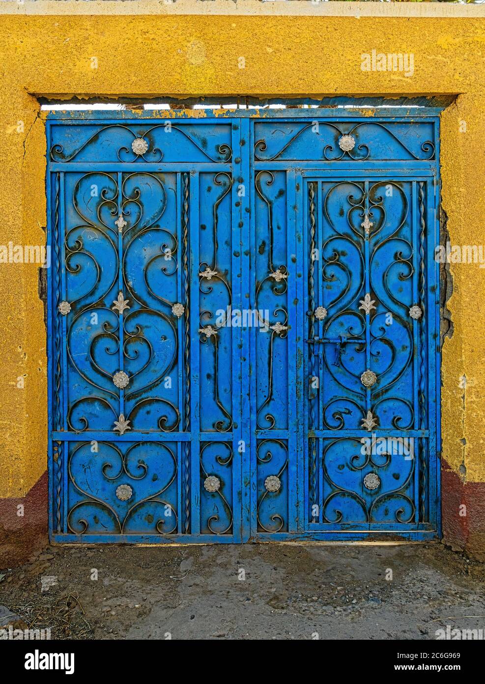 Cancello di metallo blu decorato con lavori di filigrana di ferro battuto nelle strade secondarie di un villaggio sulla riva occidentale del fiume Nilo in Egitto Foto Stock