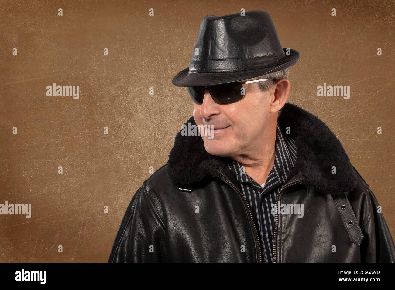 Uomo anziano che indossa cappello, giacca e occhiali da sole in pelle Foto Stock
