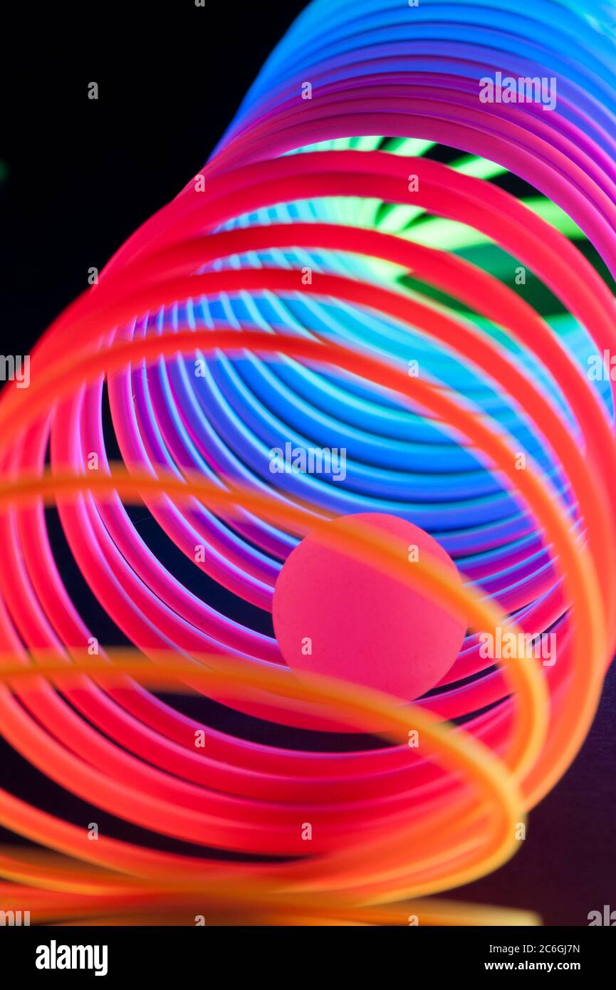 Gli oggetti circolari a spirale vengono visualizzati in modo chiuso e illuminati con colori fluorescenti su uno sfondo blu profondo. Foto Stock