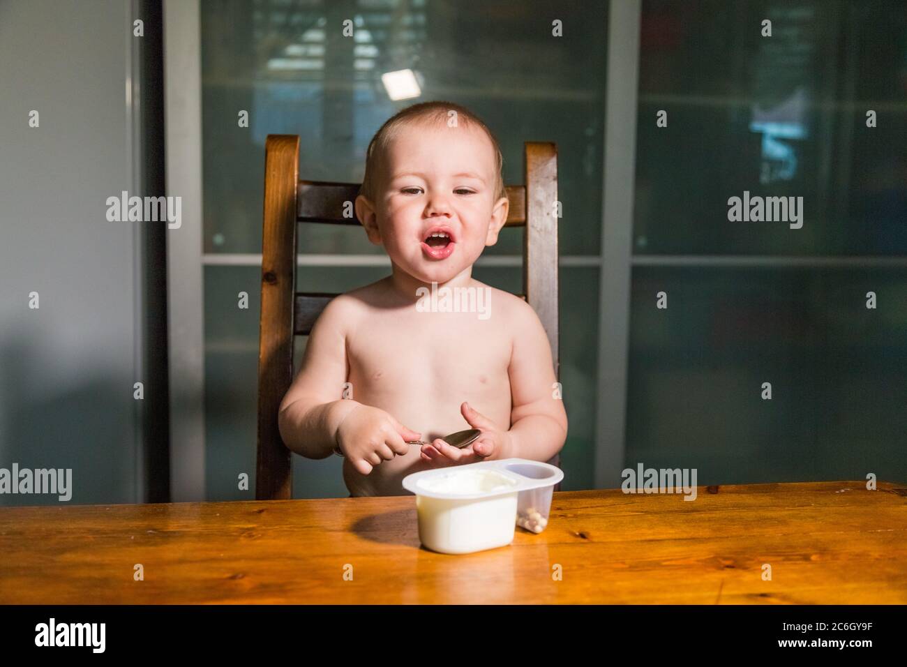 Adorabile bambino ragazzo mangiare formaggio cottage dal cucchiaio, sano snack latte. Foto Stock