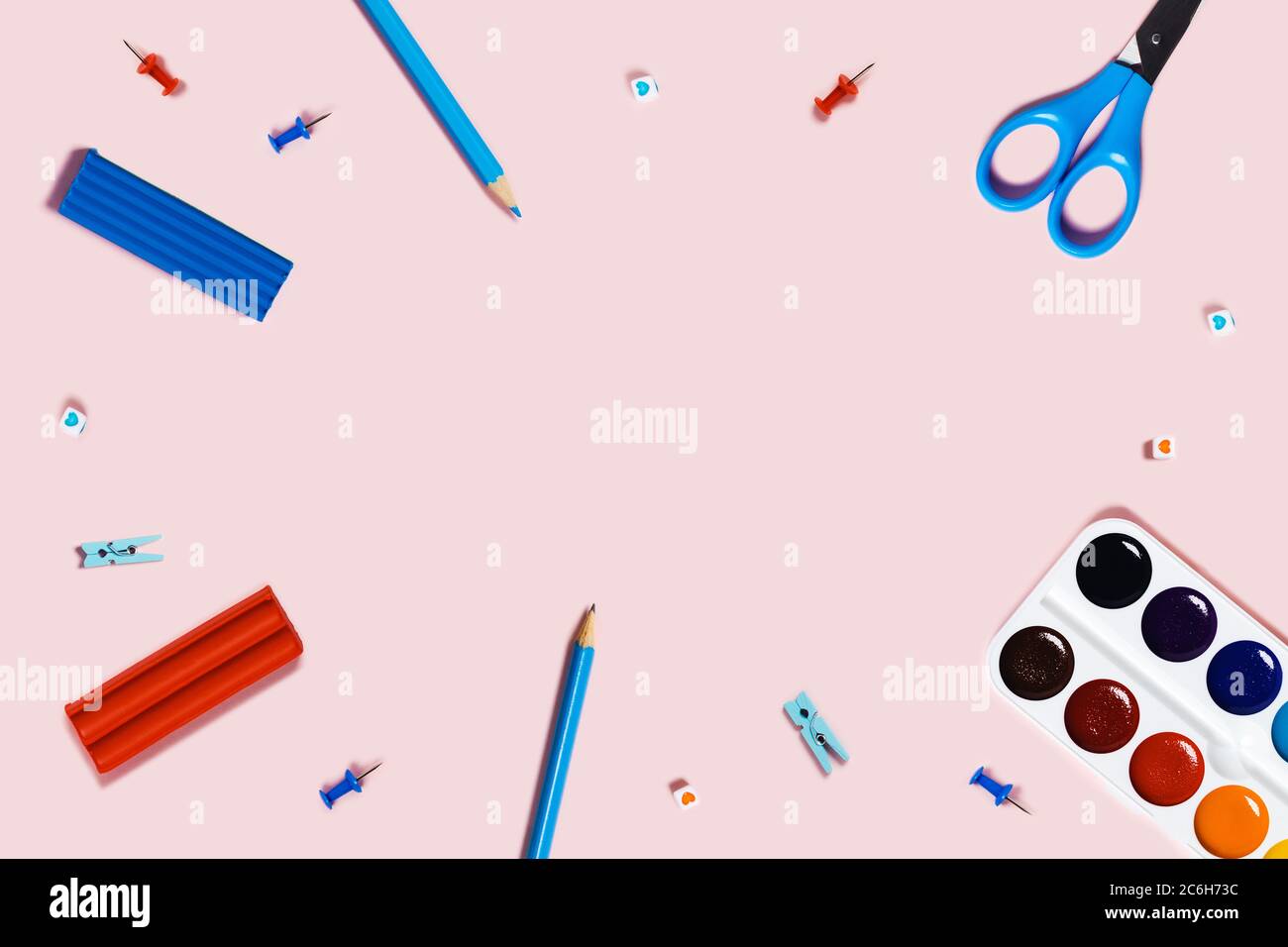 Foto di ritorno a scuola con blu e matite, graffette rosse, forbici, acquerello e plastilina su sfondo rosa. Foto Stock
