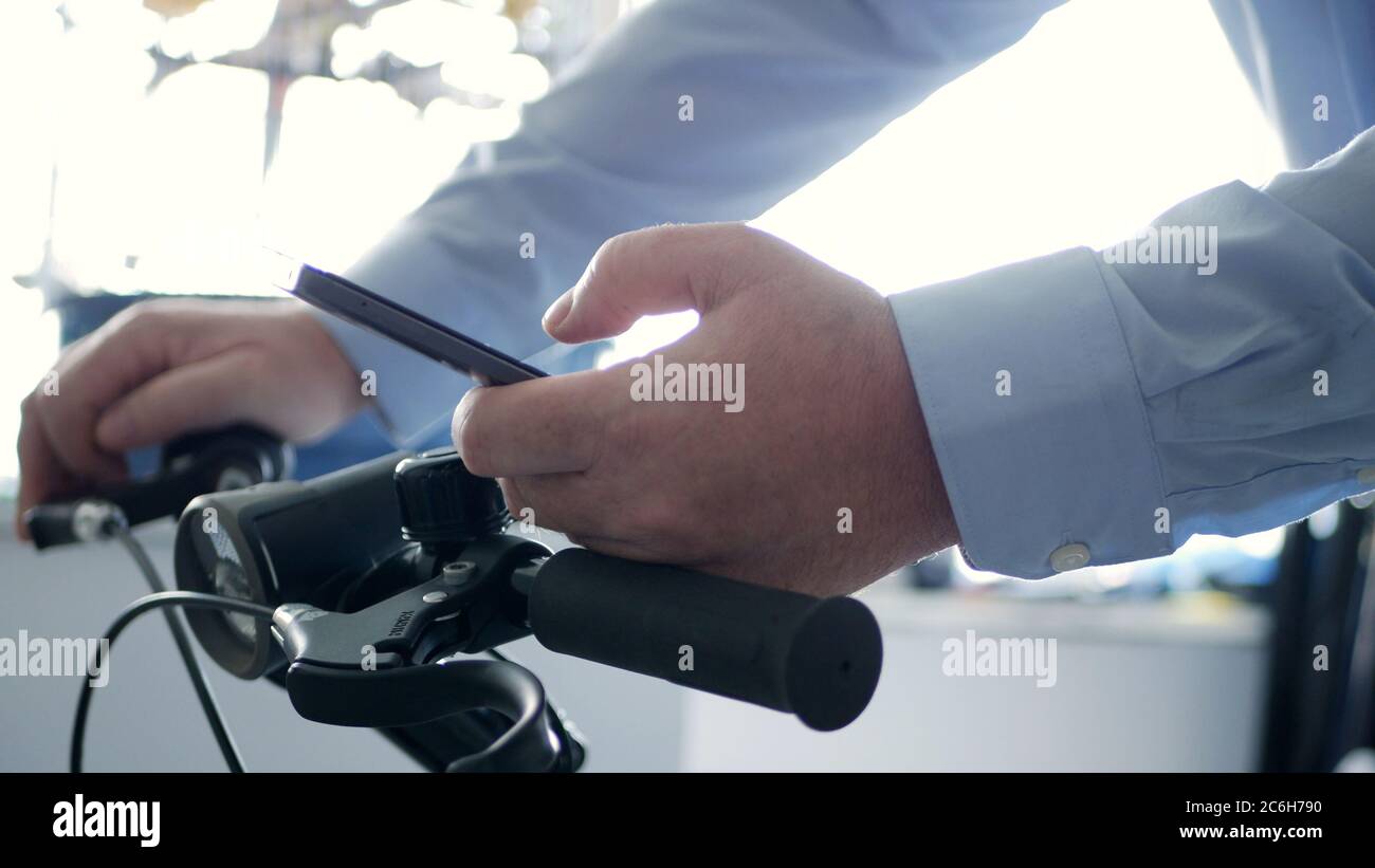 Uomo sulla bicicletta testo utilizzando un cellulare e Access Network Online applicazioni, Biker digitando un messaggio sul cellulare Foto Stock