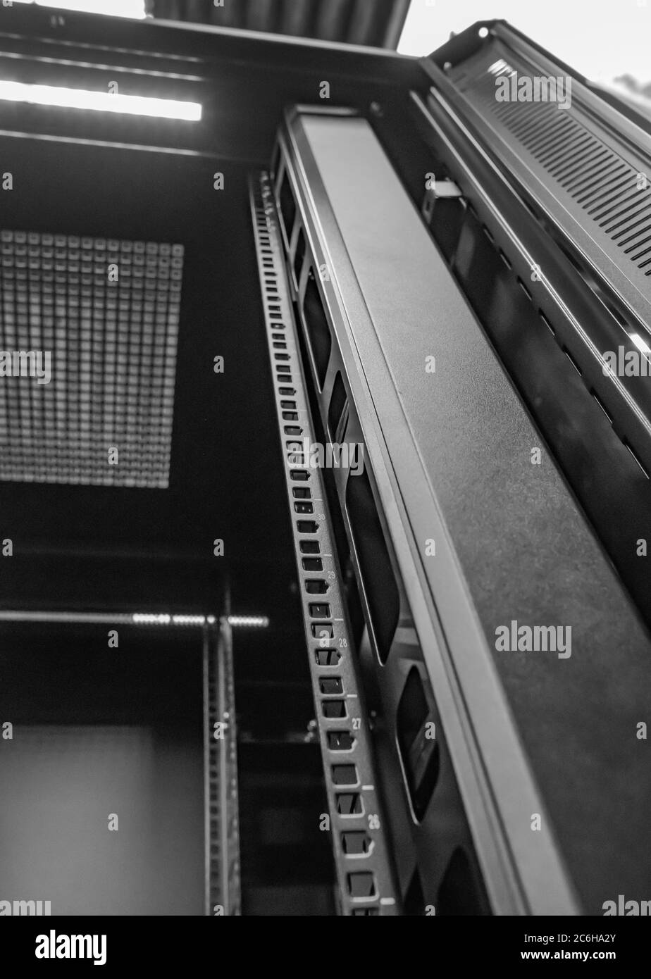 Immagine dettagliata di un computer e di un cabinet per server di rete che mostra i montanti interni per rack da 19 pollici. Visto in un data center per l'hosting di server IT. Foto Stock